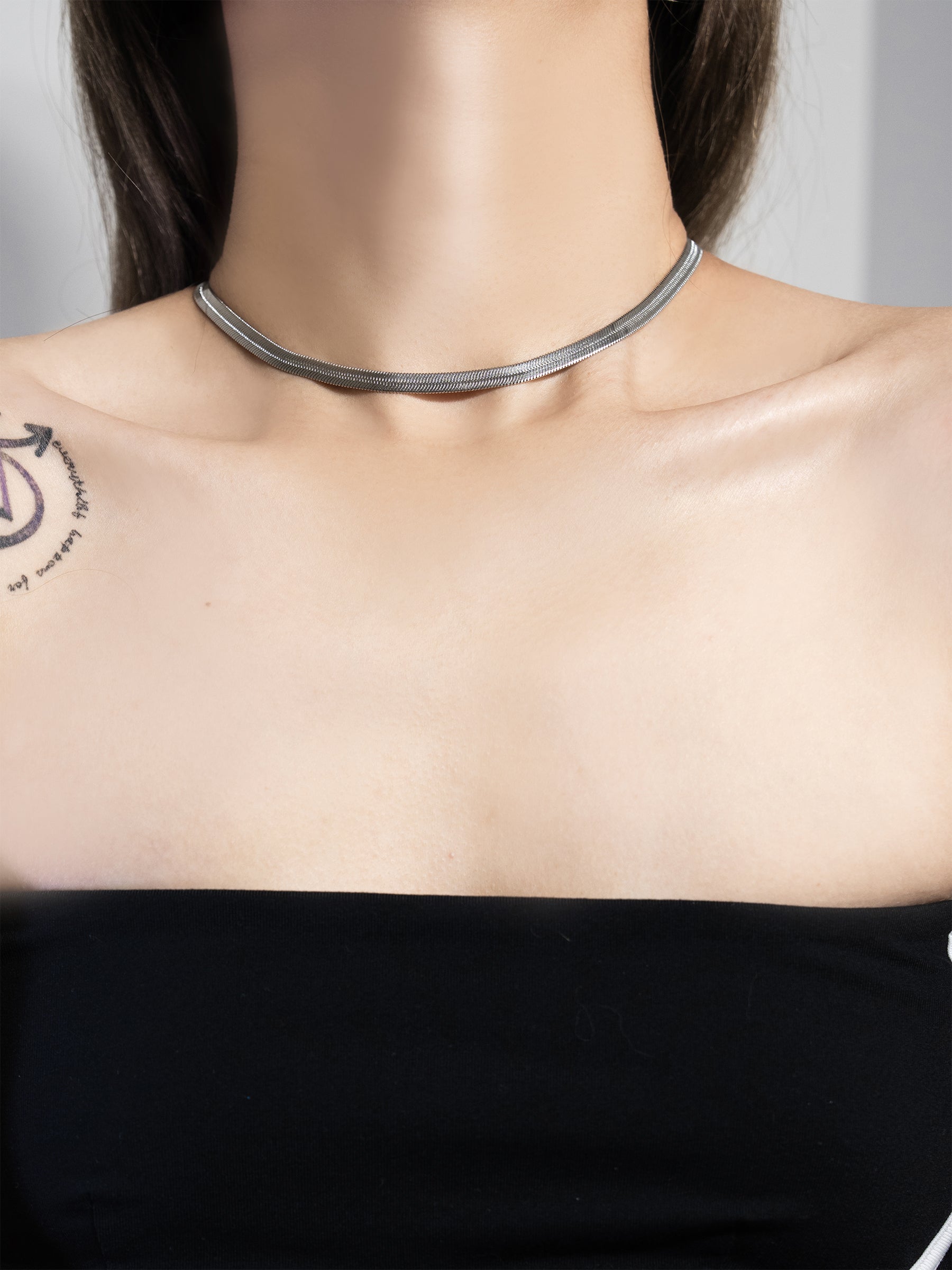 Minimalist snake chain choker necklace waterproof worn elegantly on model's neck.